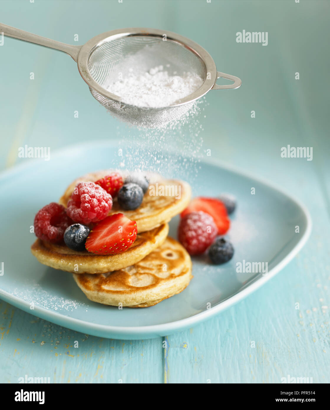 Setacciatura di glassa di zucchero sulla frutta e frittelle Foto Stock