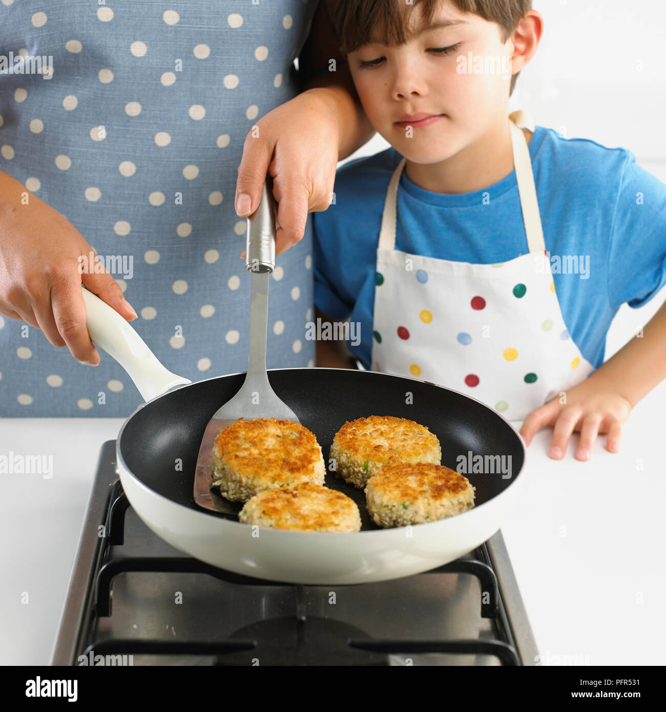 Donna e bambino fishcakes frittura, 7 anni Foto Stock