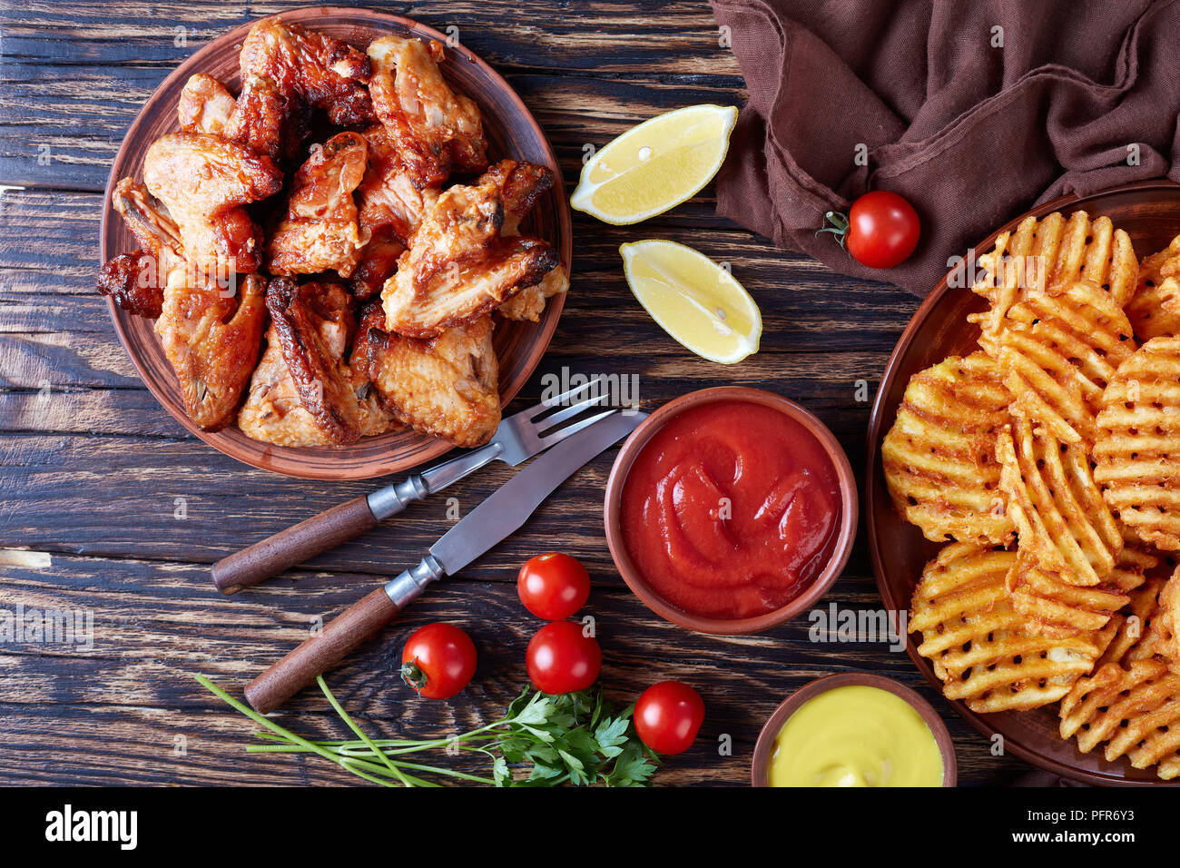 Criss Cross Fries su una argilla piastre su un tavolo di legno con senape e salsa di pomodoro dipping, vista da sopra, piana, laici close-up Foto Stock