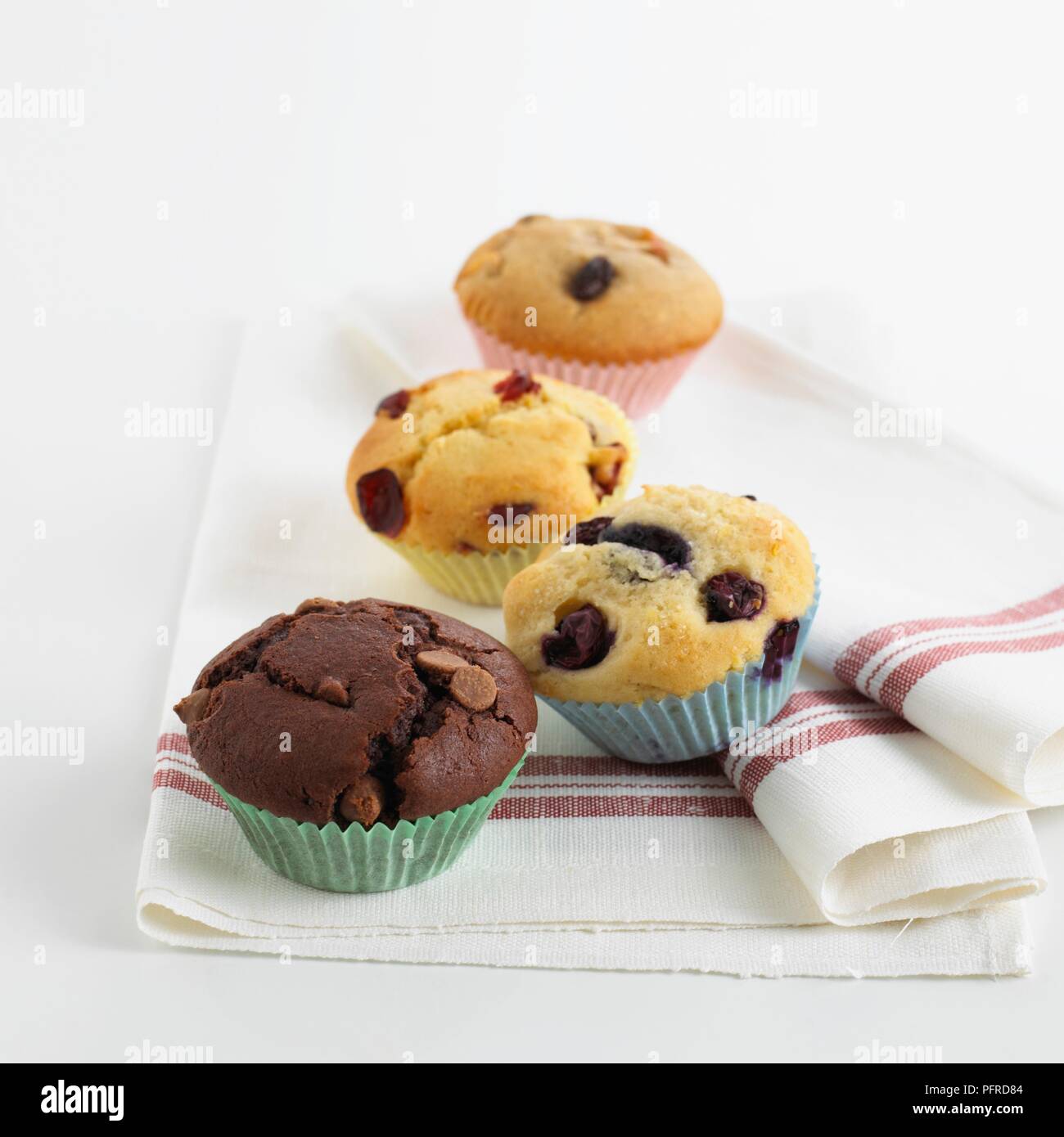 Una selezione di muffin su un canovaccio, compresi chocolate chip muffin, muffin ai mirtilli, cranberry muffin, muffin passito Foto Stock