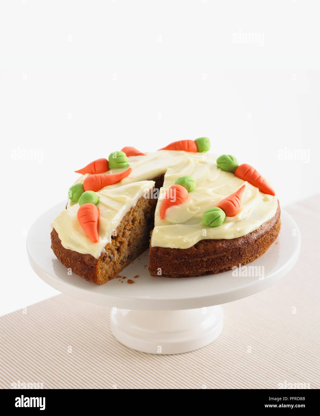 Torta di carote con glassa di formaggio cremoso e carota decorazione su una torta stand, singola fetta tagliata via Foto Stock