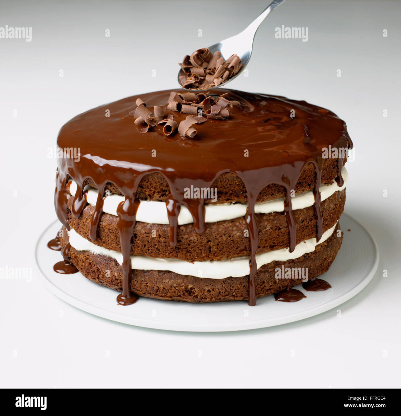 Spargendo i riccioli di cioccolato sul cioccolato e crema torta Foto Stock