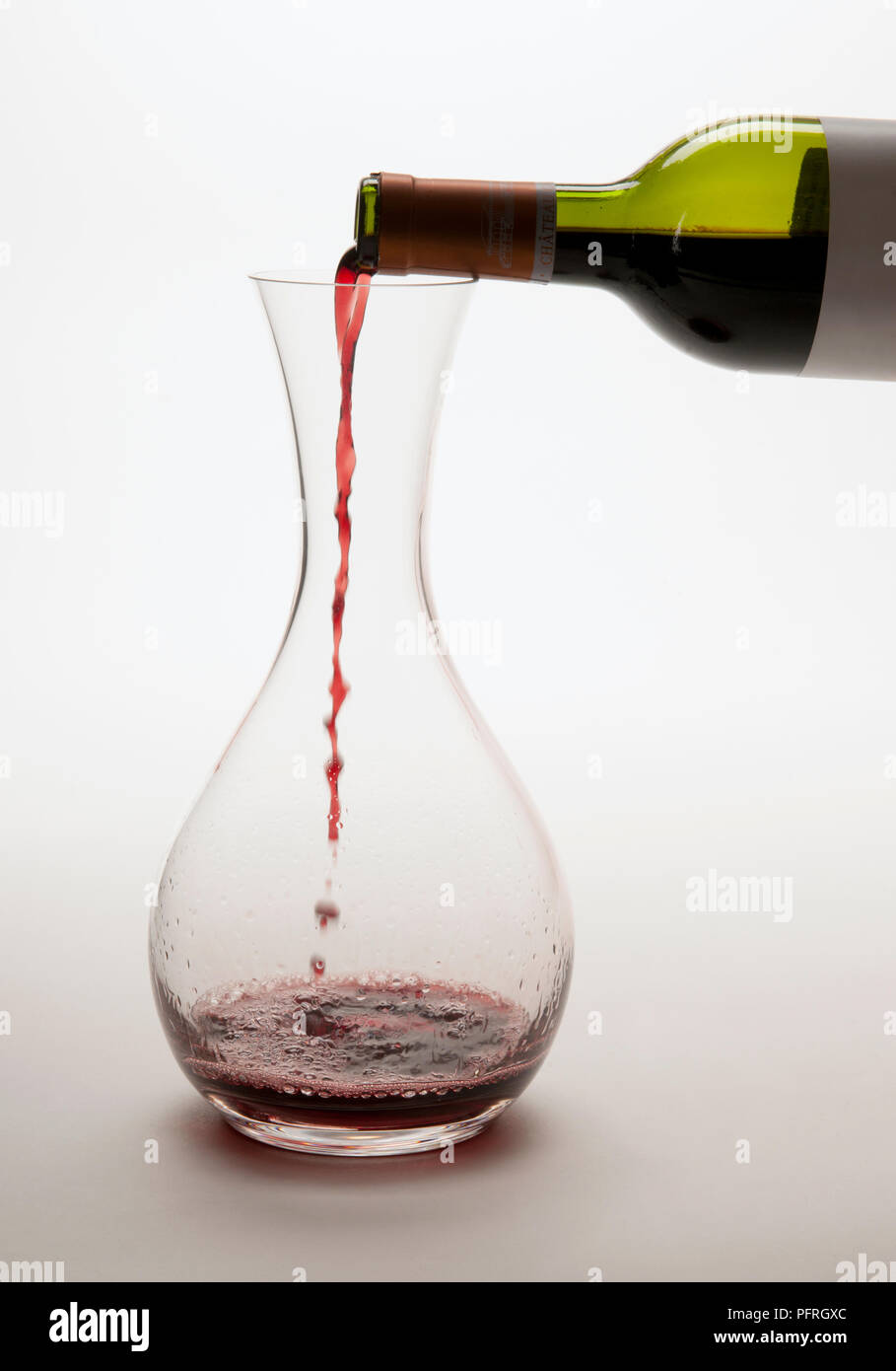 Versando il vino rosso dalla bottiglia nella caraffa di vetro Foto Stock