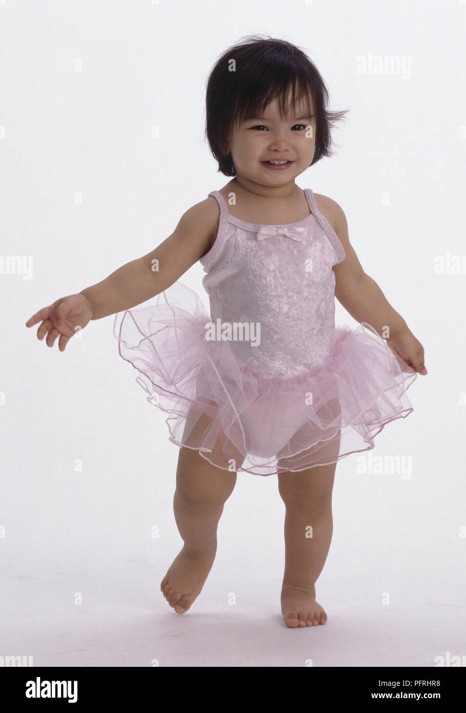 A piedi nudi toddler sorridente indossando rosa ballerina tutu Foto Stock
