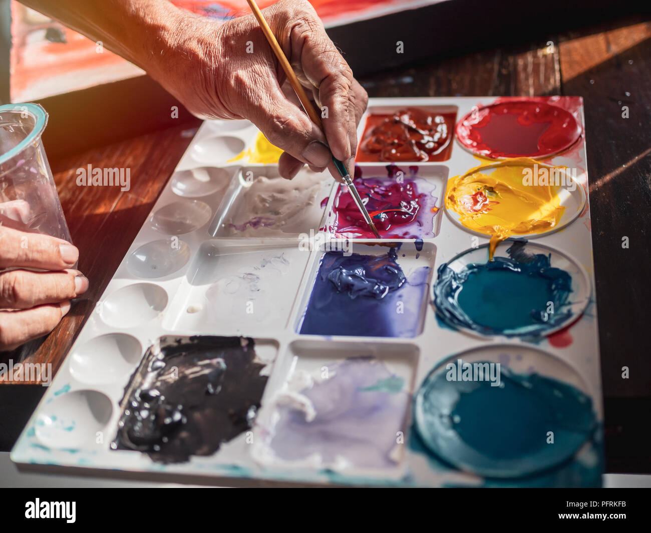 Mano di artista miscelazione colore acrilico da pennello nella tavolozza dell'artista sul tavolo di legno sfondo per il lavoro in studio d'arte. Foto Stock