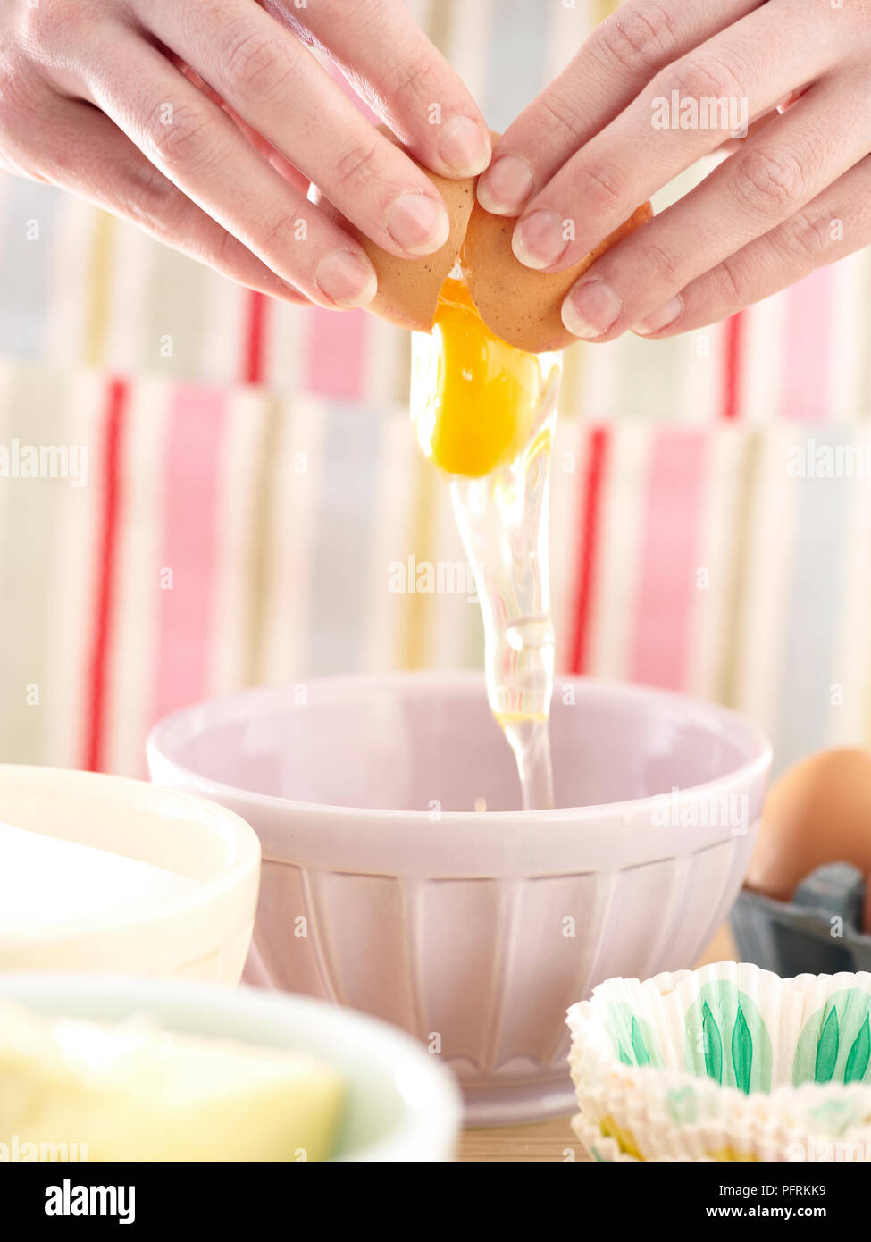 Uovo di cracking in un recipiente, close-up Foto Stock