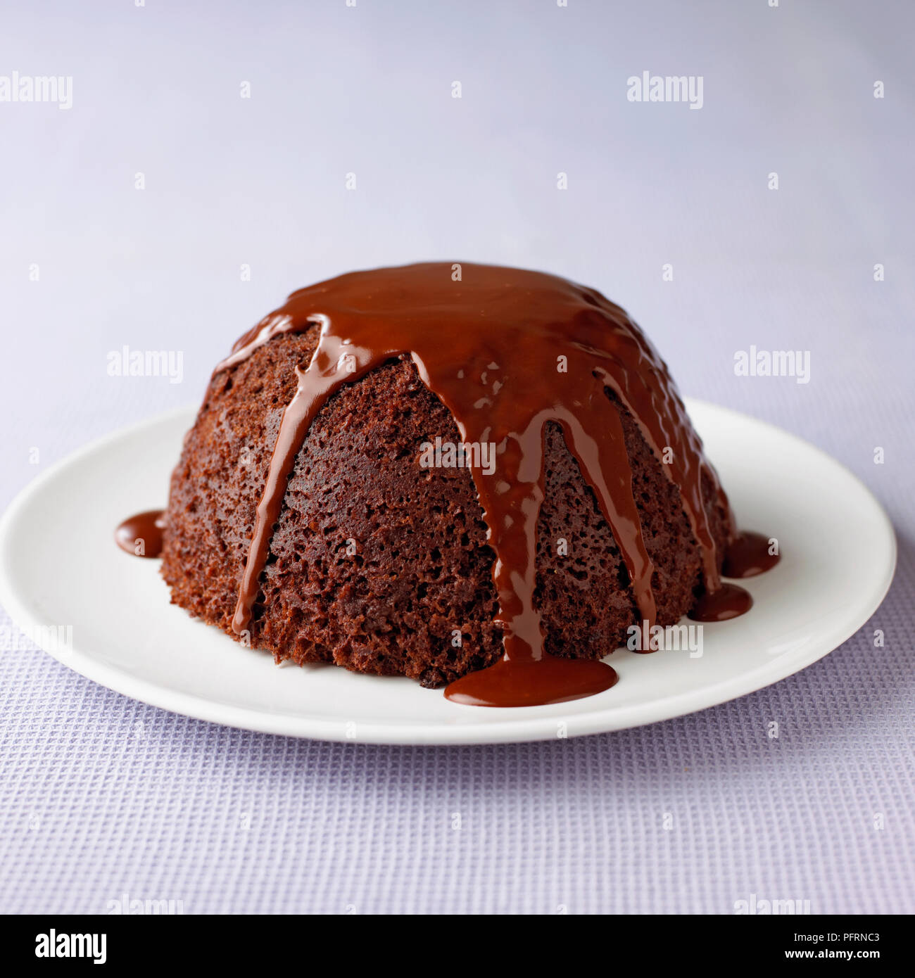 Spugna di cioccolato budino di gocciolamento con salsa al cioccolato servito sulla piastra bianca sul tavolo, close-up Foto Stock