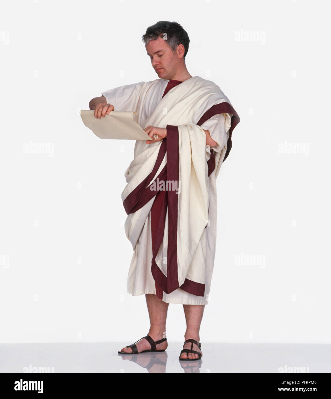 Uomo vestito come cittadino romano che indossa toga e tenuta di scorrimento carta Foto Stock