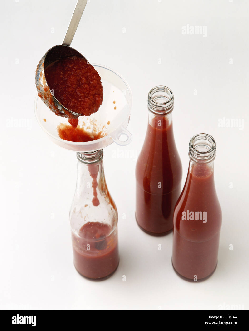 Bottiglie che vengono riempiti con fatti in casa a base di salsa di  pomodoro, usando un imbuto Foto stock - Alamy
