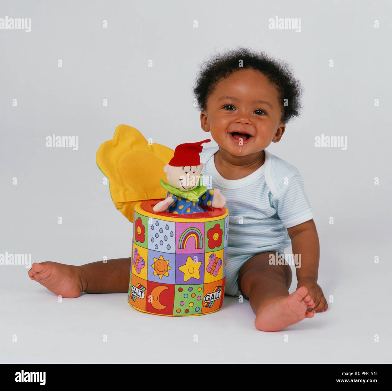 Baby boy (8,5 mesi) seduto sul pavimento con pop-out clown giocattolo davanti a lui Foto Stock