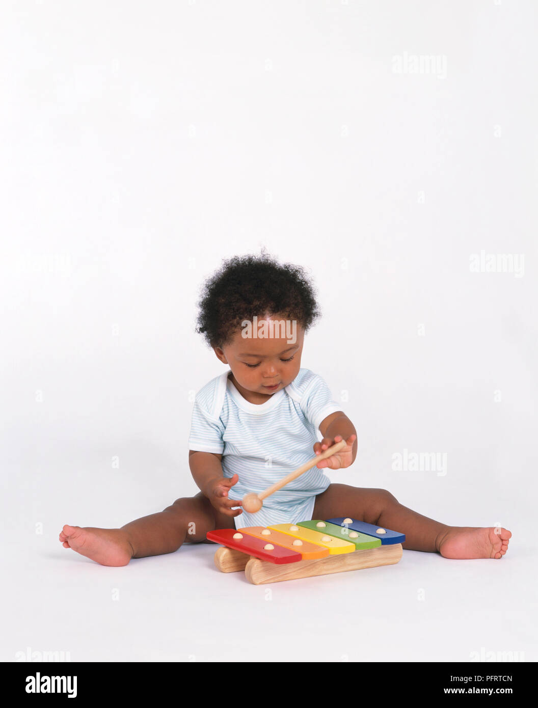 Baby boy giocando con xilofono e il battitore, seduto sul pavimento Foto Stock