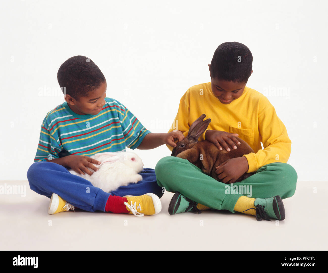 Due ragazzi seduti con un coniglio ciascuno sul loro giro Foto Stock