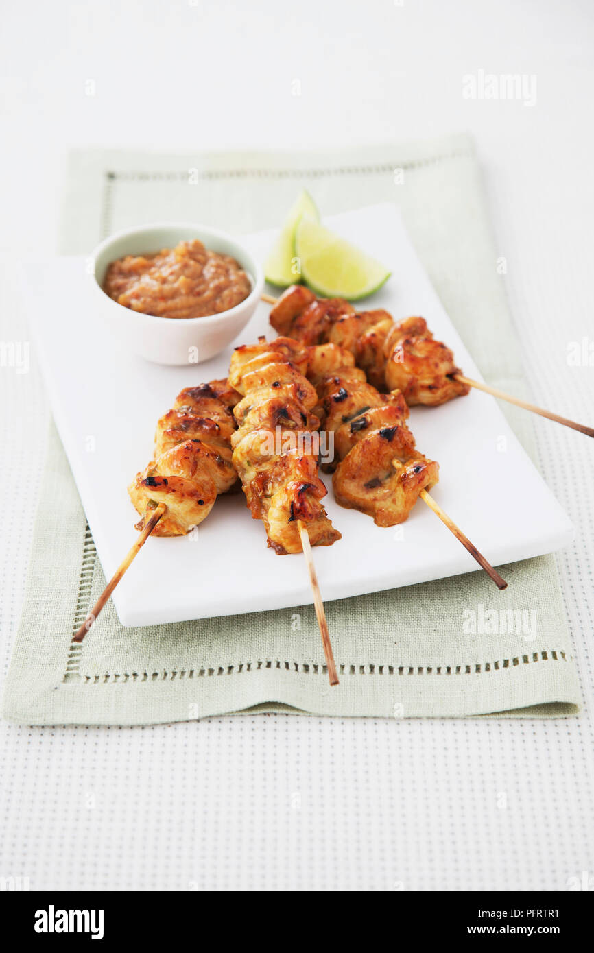 Satay di pollo con salsa di arachidi e spicchi di lime Foto Stock