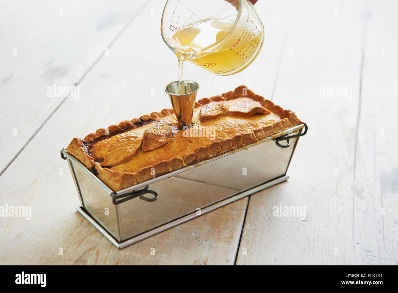 Versare il brodo in un paté de Gibier en crostino Foto Stock