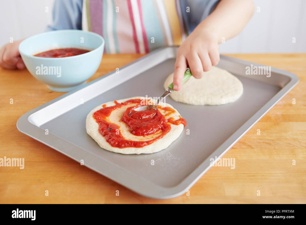 Ragazzo salsa di spandimento su una base per pizza Foto Stock