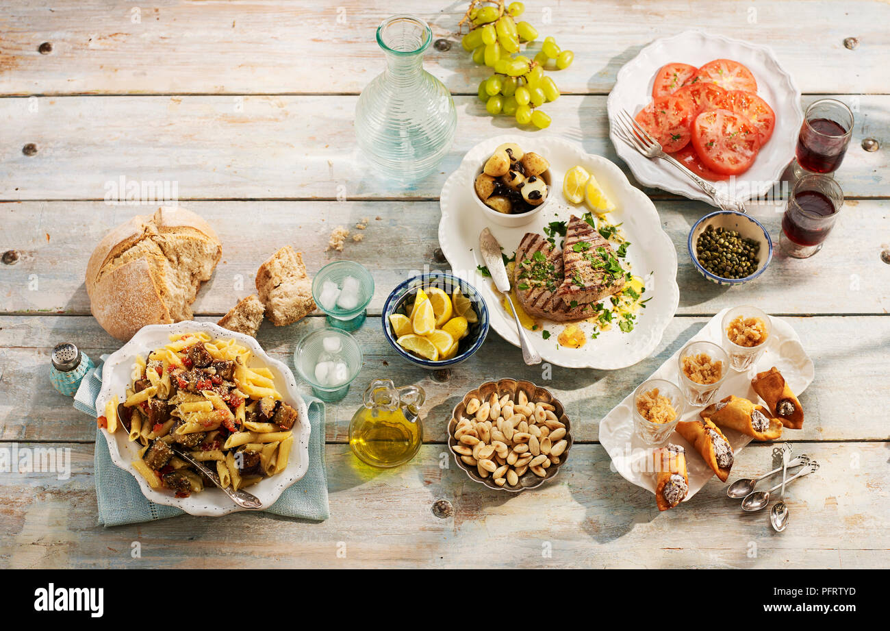 Pranzo siciliano, compresa la pasta alla norma, Pesce spada in salmoriglio, granita di caffe espresso, mandorle tostate, cannoli Foto Stock