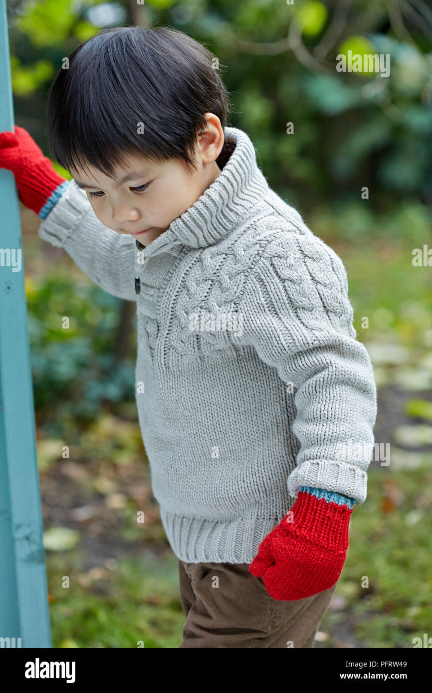 Ragazzo (2,5 anni) indossare ponticello a maglia e guanti Foto Stock