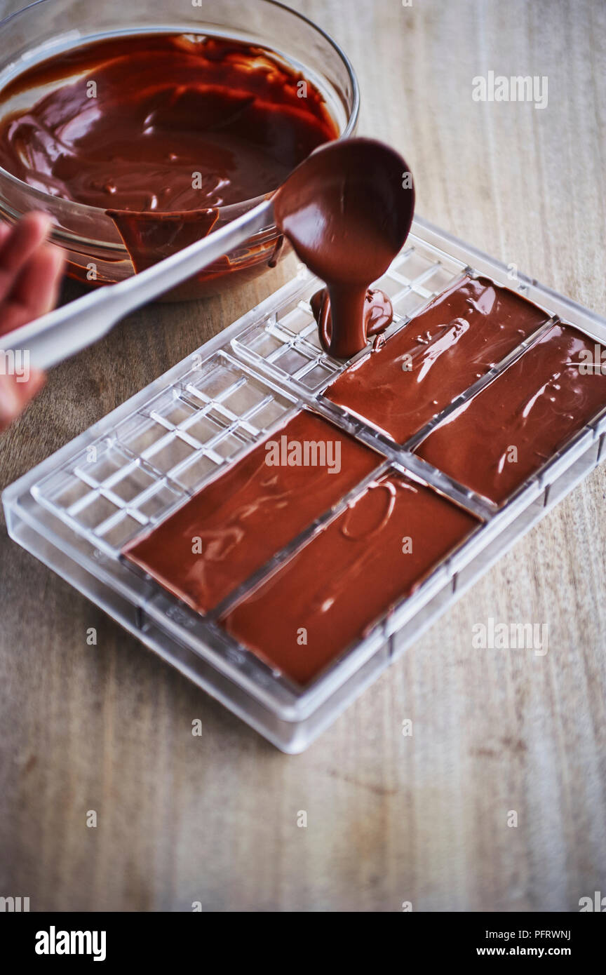 La produzione del cioccolato di barre e di lastre, versando il cioccolato fuso in stampi Foto Stock