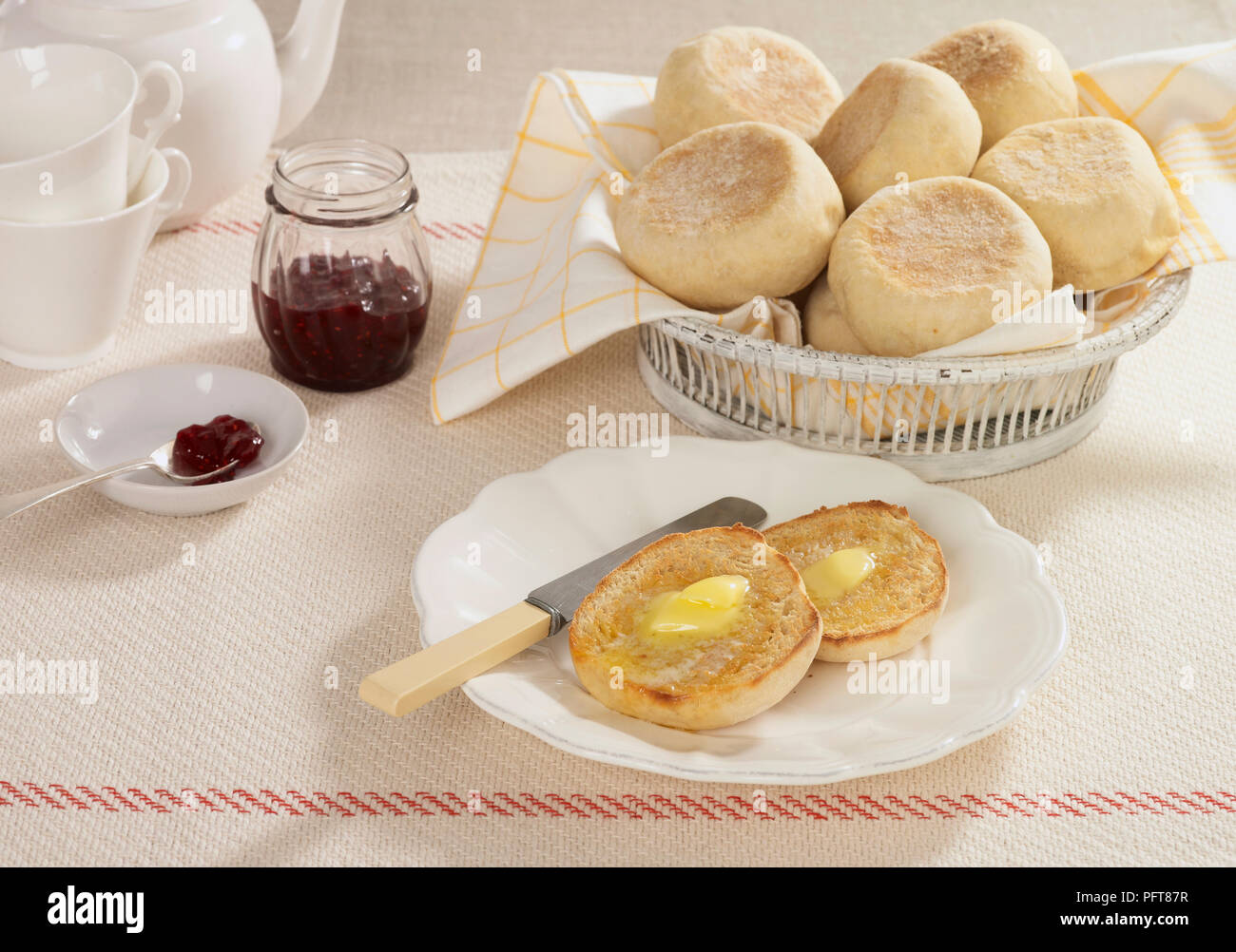 Muffin inglese servita su piastra in fusione con burro e marmellata e nel carrello Foto Stock