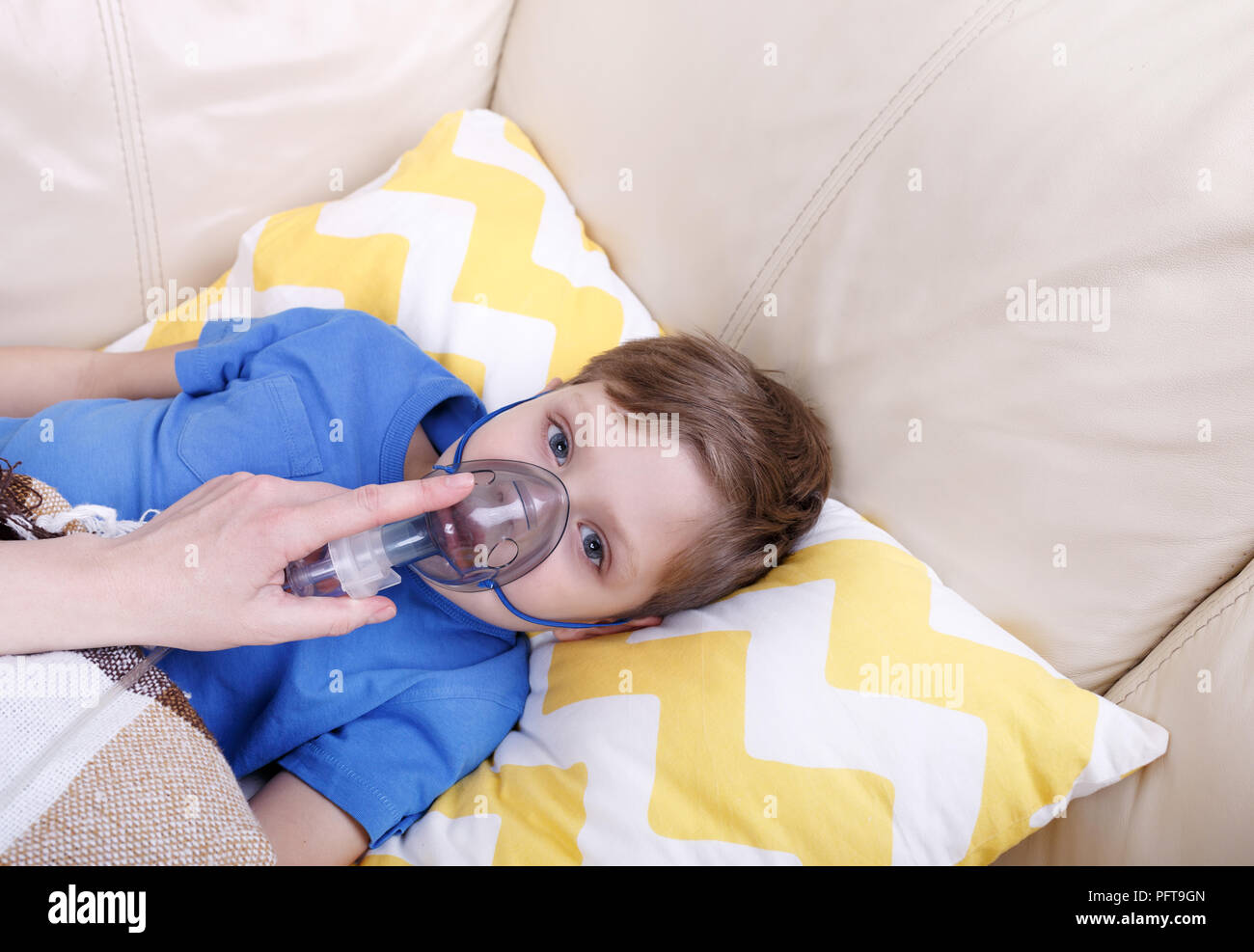 Ragazzo di respirare attraverso il nebulizzatore. Malati chid con nebulizzatore pediatrica. Foto Stock