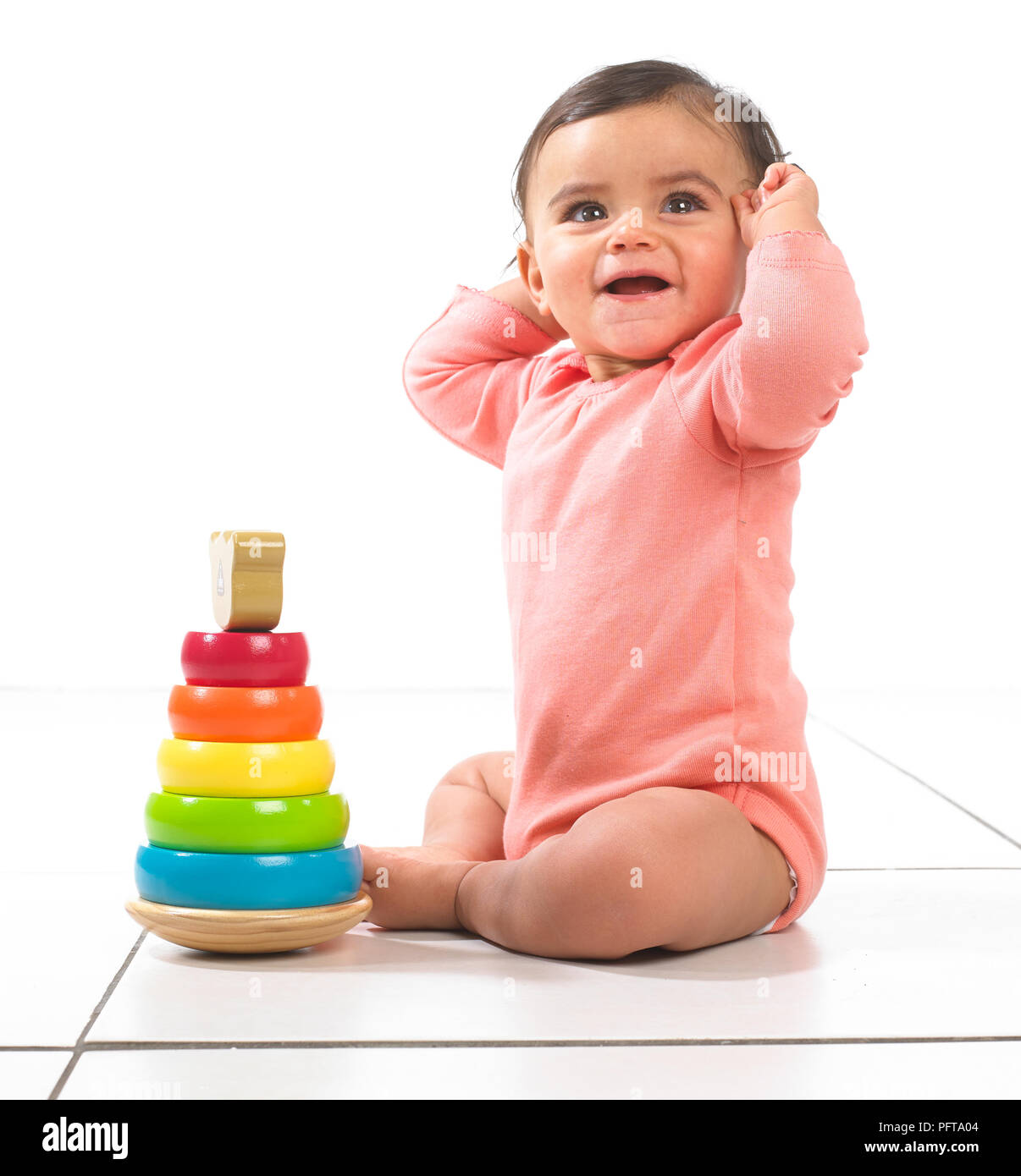Baby ragazza seduta giocando con anello impilabile toy, 7 mesi Foto Stock