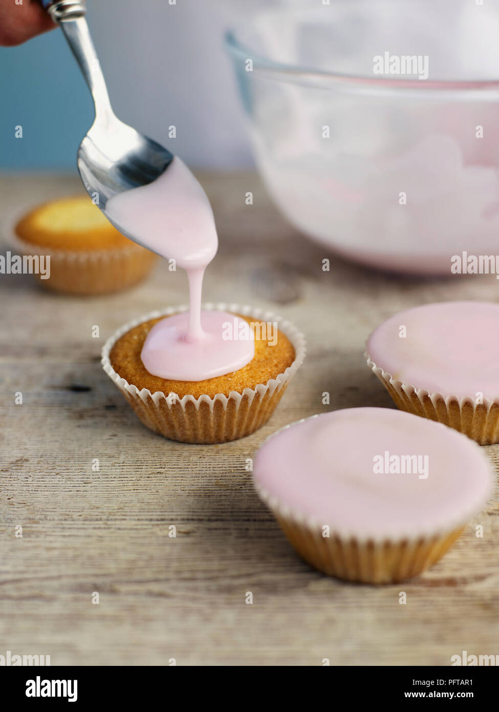 Colata di glassa rosa oltre i tortini Foto Stock