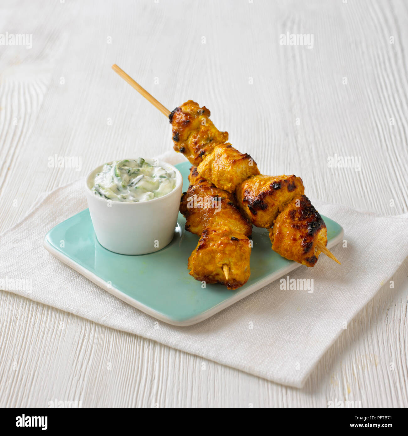 Pollo Tikka spiedini con il cetriolo e menta raita Foto Stock