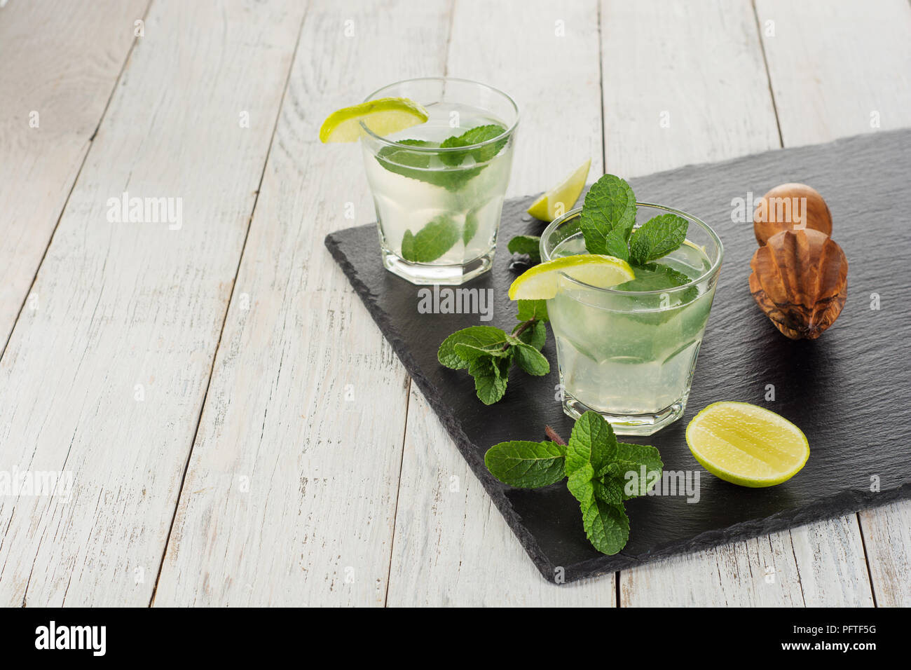 Bevanda estiva. Citrus limonata con la menta e il ghiaccio sul bianco sullo sfondo di legno. Foto Stock