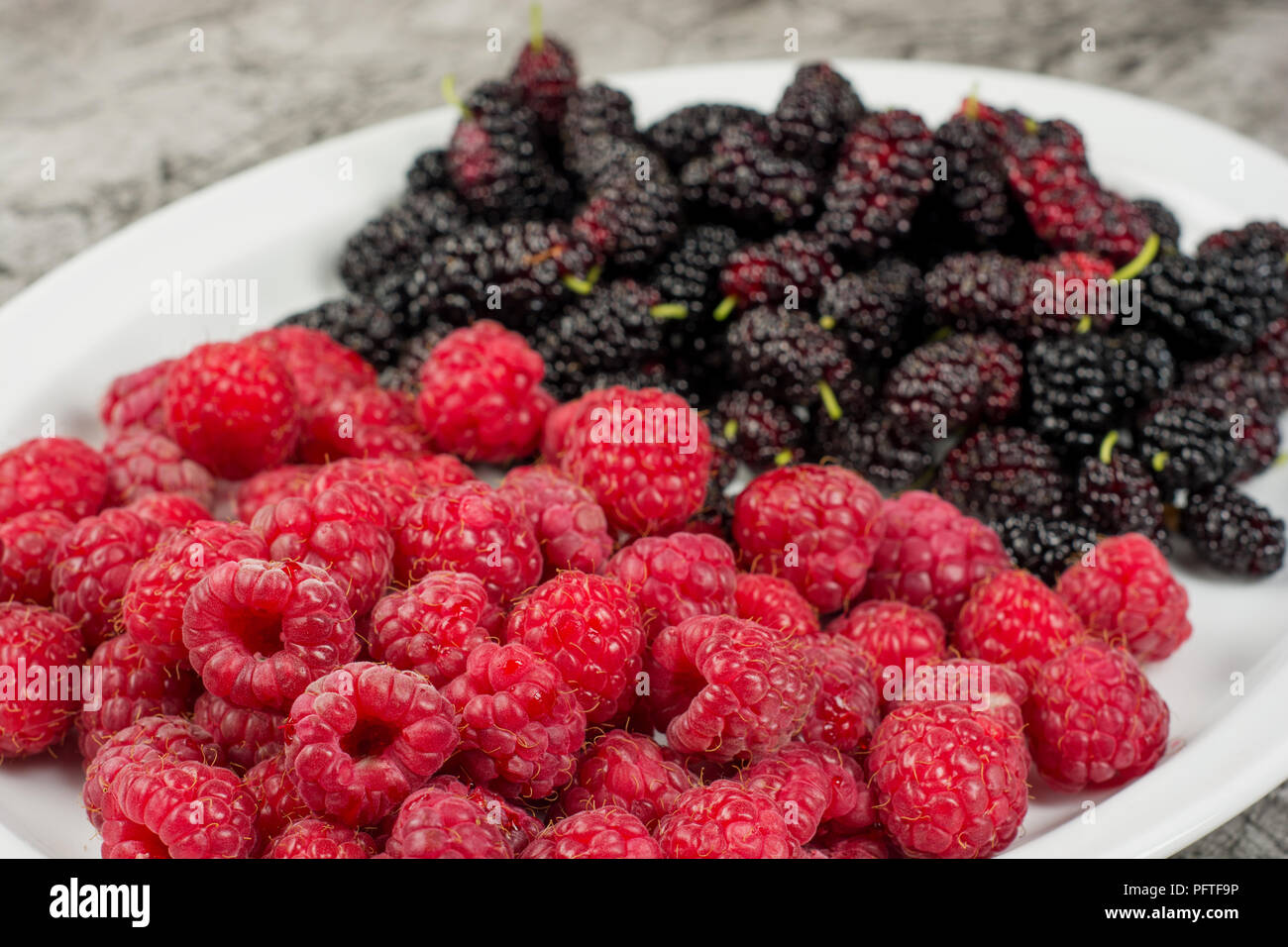 Piastra con lamponi e Mulberry. Frutti di bosco freschi sulla piastra vicino. Foto Stock