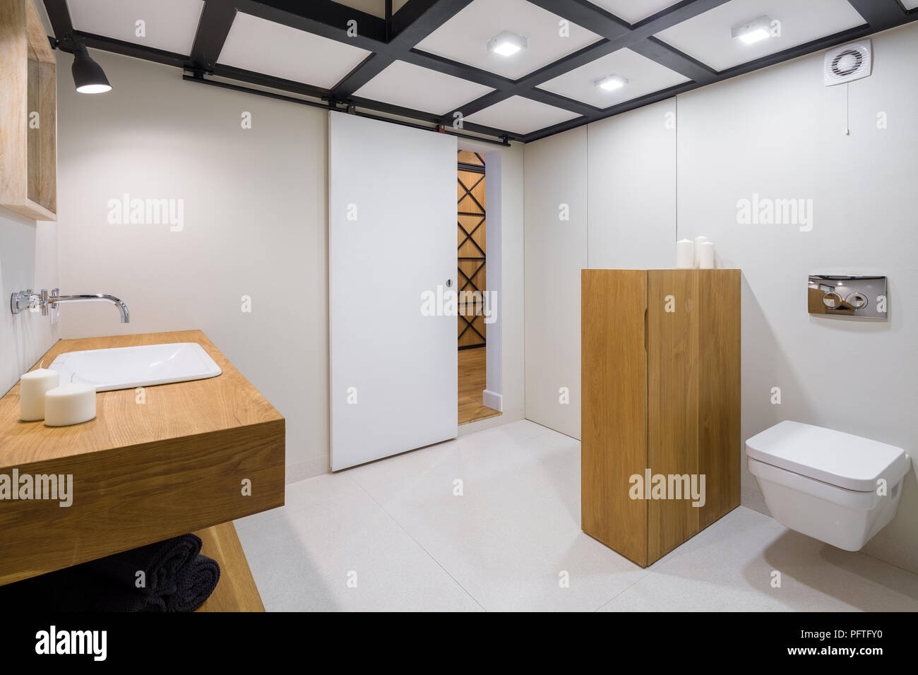 Bagno bianco con arredi in legno e travi a soffitto Foto Stock