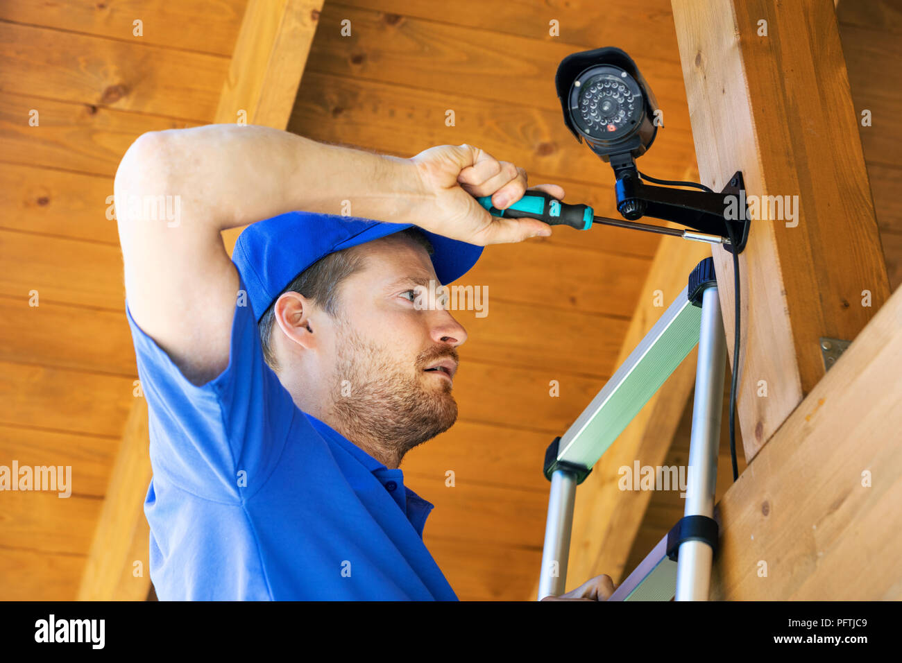 Il tecnico installa videocamera di sorveglianza in casa carport Foto Stock