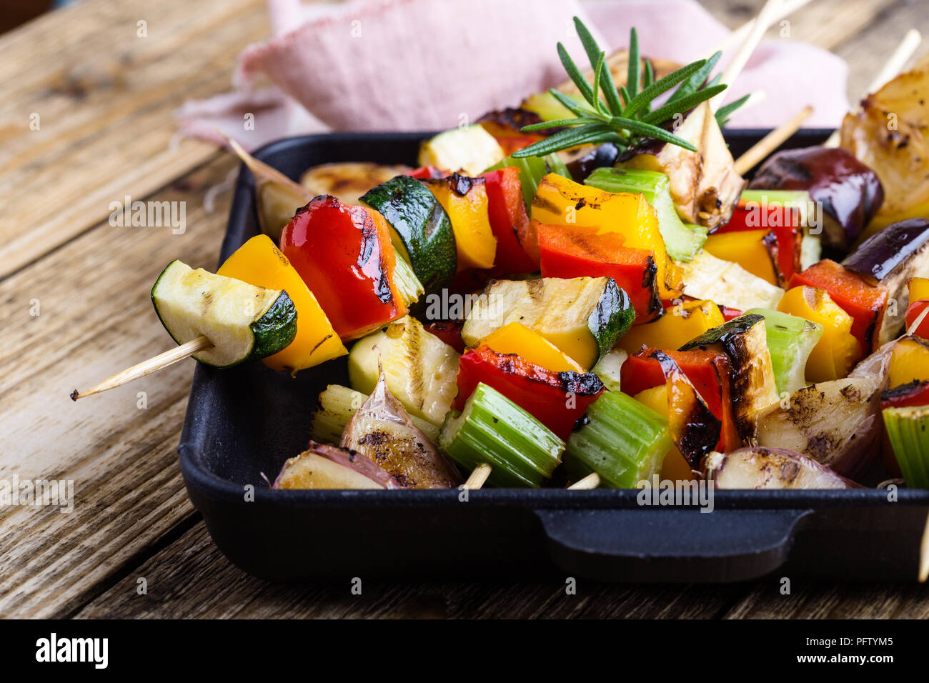 Grigliata di verdure colorate spiedini sulla padella in ghisa. Vegano pasto estivo su tavola in legno rustico Foto Stock