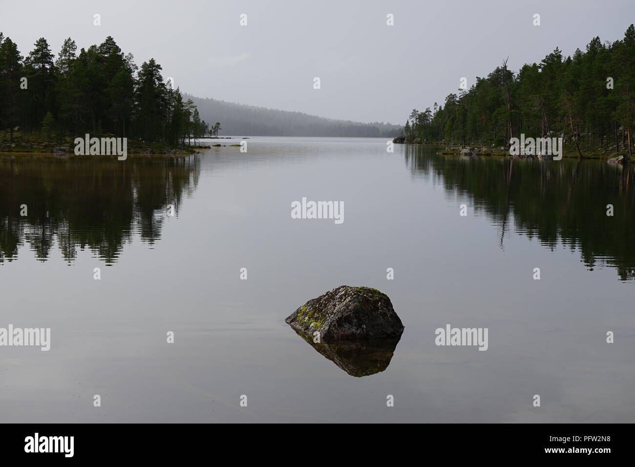 La riflessione sul tranquillo lago circondato da foresta in Lapponia, Finlandia Foto Stock