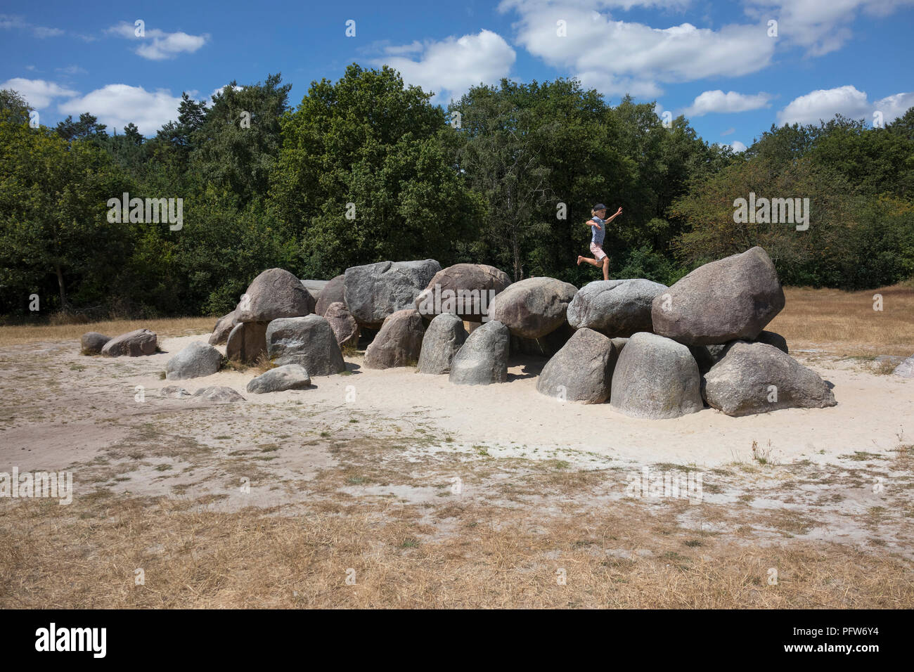 Havelte, Drenthe, Paesi Bassi - 14 Luglio 2018: bambino saltando sulle pietre di una vecchia tomba di pietra come un grande dolmen in Drenthe Olanda, chiamato in olandese Foto Stock