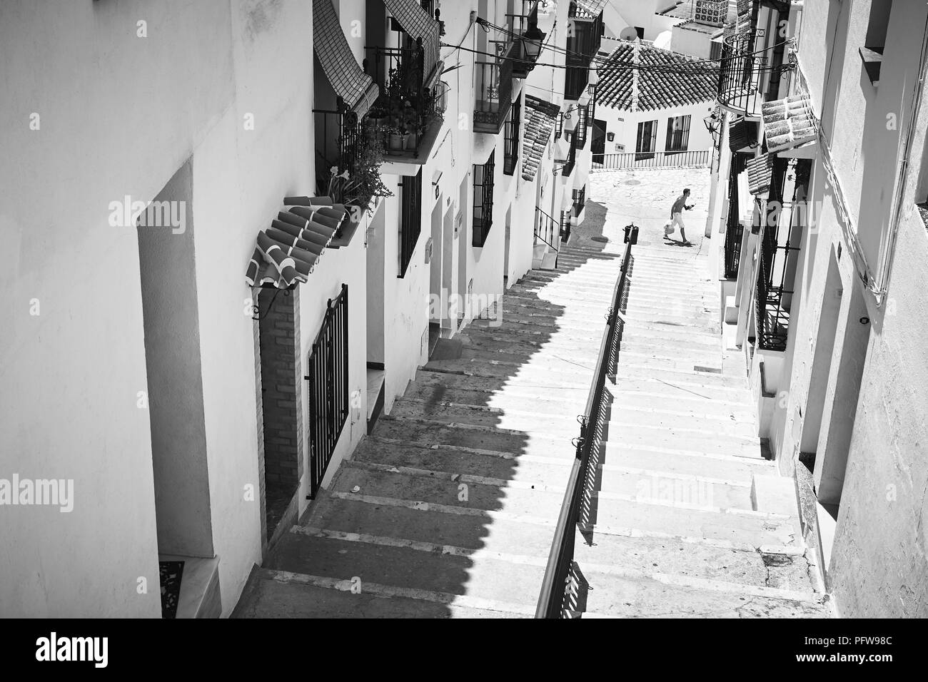 Foto in bianco e nero guardando giù le fasi di una stretta strada spagnolo di bianco Case Murate in Mijas, Andalusia nel sud della Spagna Foto Stock