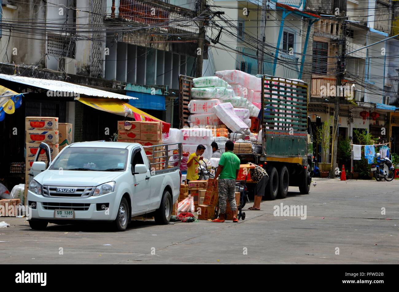 Gli uomini lo scarico delle merci su un carrello sul lato strada market bazar Pattani Thailandia Foto Stock