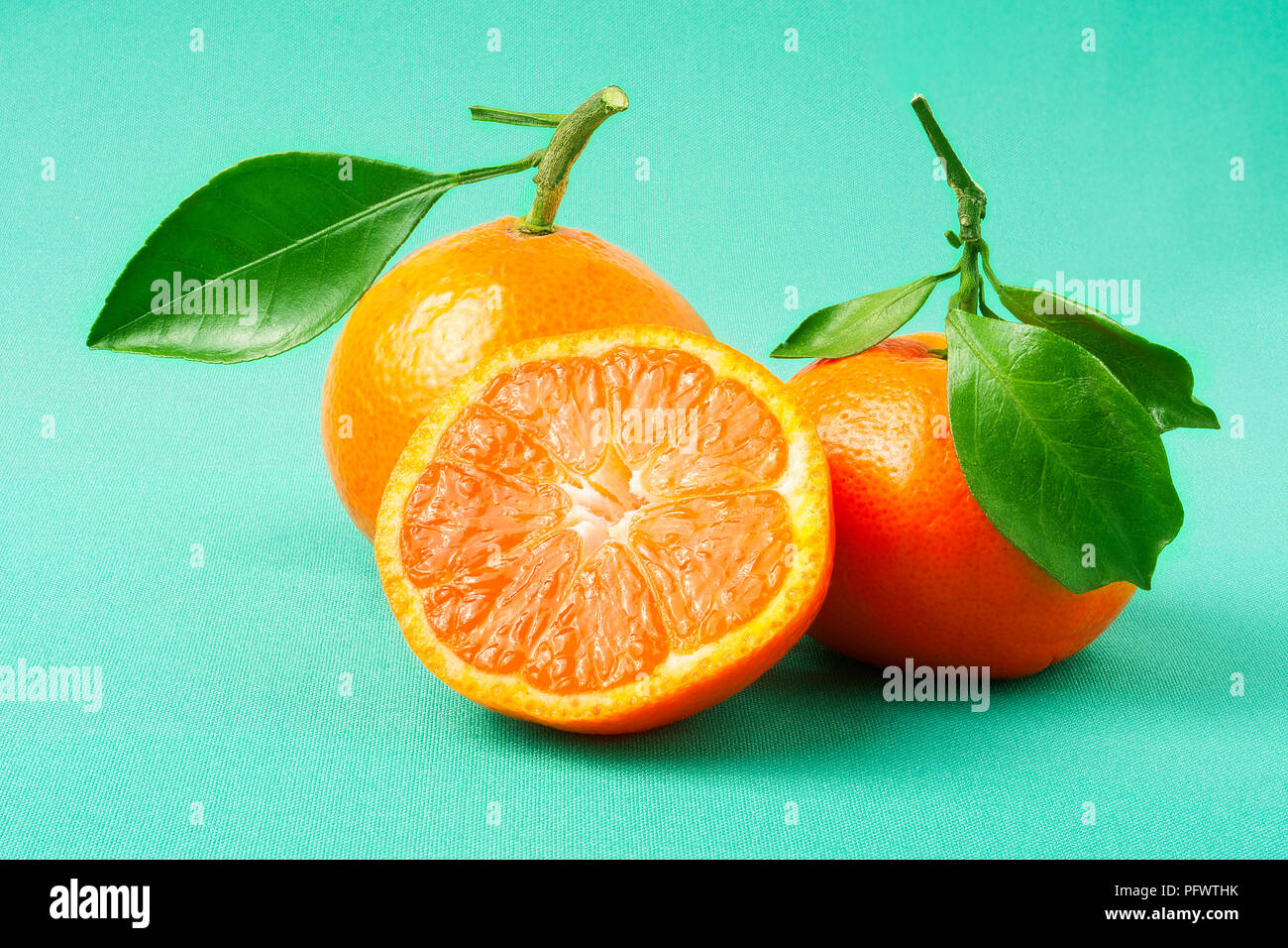 Due nuove tangerine su uno sfondo verde Foto Stock