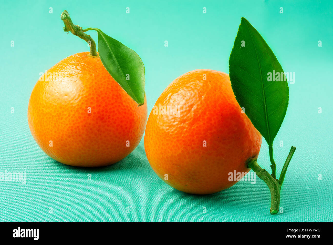 Due nuove tangerine su uno sfondo verde Foto Stock
