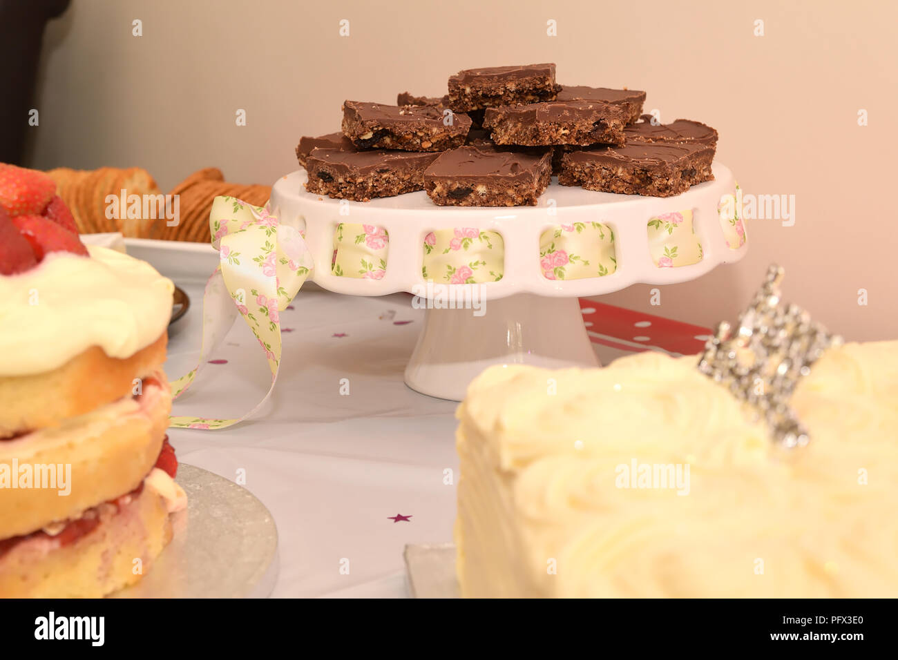 Fette di ristorante Tiffin torta al cioccolato biscotto su una torta stand con pretty pink ribbon su un tavolo per una festa di compleanno a buffet Foto Stock
