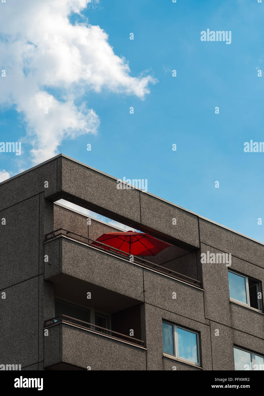 L'ombrellone rosso sul balcone sul blocco di appartamenti Foto Stock