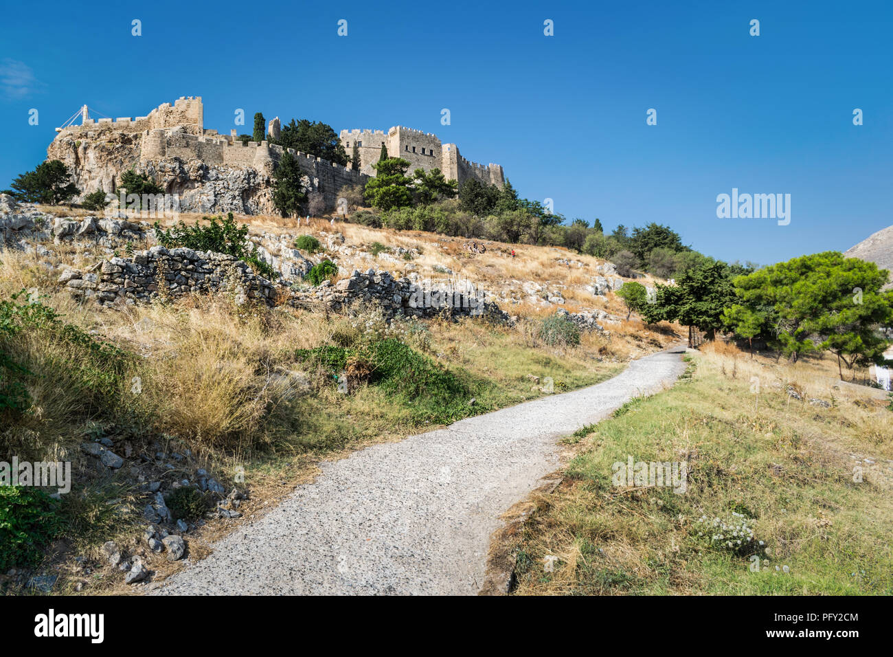 Thi è la vecchia strada di pietra che le curve che fino all'acropoli di Lindos sul isola greca di Rodi. Asini di assumere persone al Castello Foto Stock