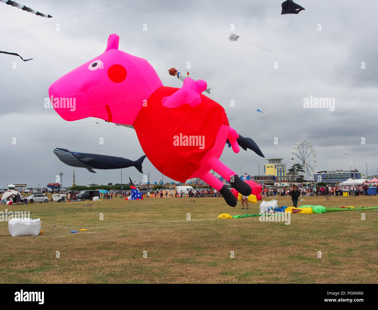 Una Peppa Pig aquiloni contro un cielo nuvoloso a Portsmouth internation kite festival, Inghilterra Foto Stock