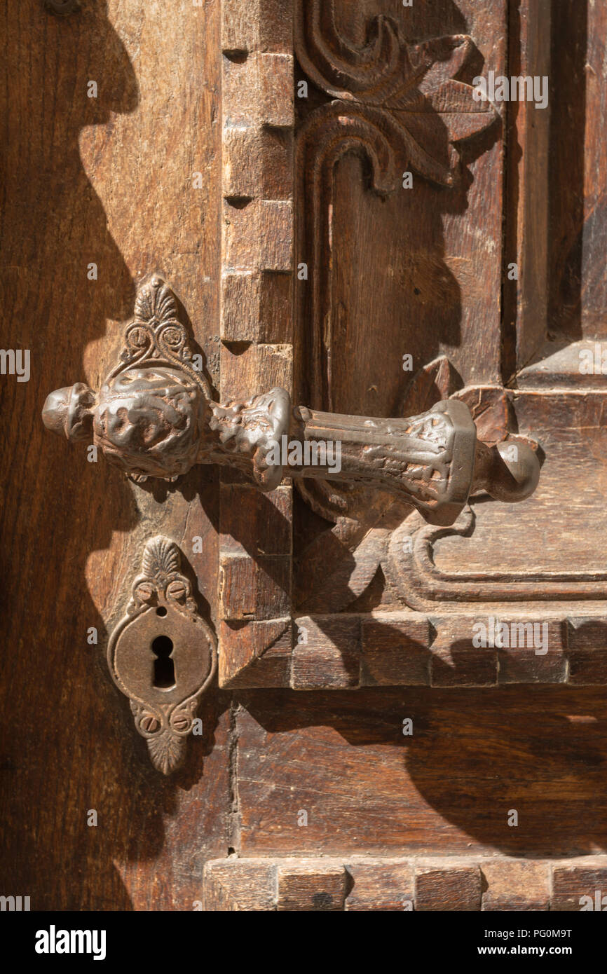 Ornati usurato vecchio arrugginito metallo ferro la maniglia dello sportello e la serratura con toppa sul scolpito decorativo colorato marrone porta di legno sulla giornata di sole a Kotor, Montenegro. Foto Stock