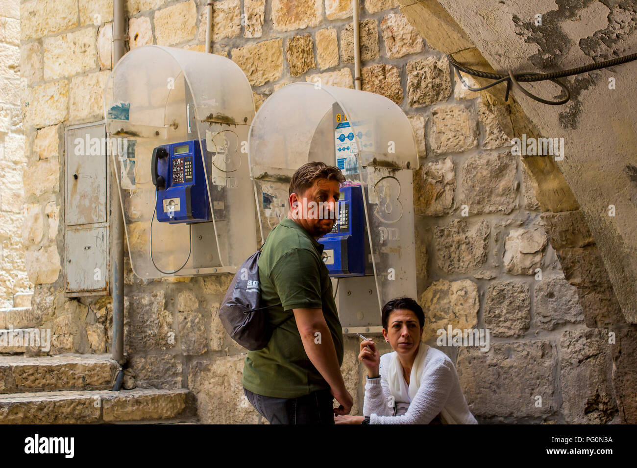 10 maggio 2018 turisti prendono tempo fuori accanto a una coppia di telefoni pubblici nella vecchia città murata di Gerusalemme Israele Foto Stock