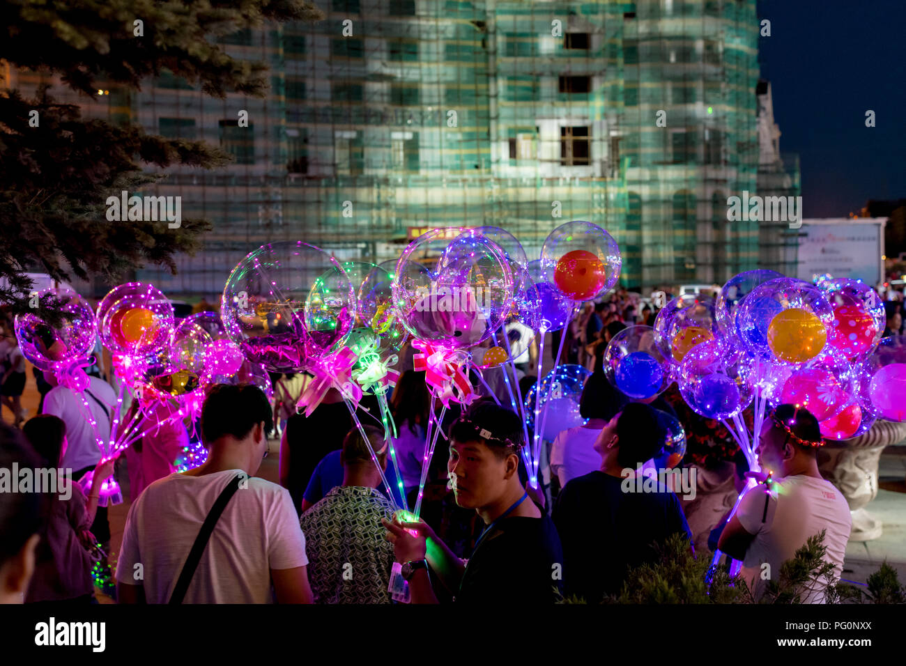 Persone azienda illuminato a LED palloncini pieni di giocattoli e palloncini, notte, serata elio Foto Stock