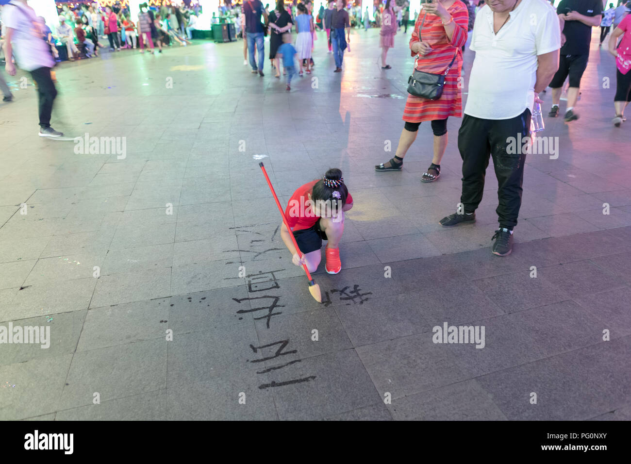 Bambina, acqua-disegno sul marciapiede, spazzola grande acqua notte di scrittura Foto Stock