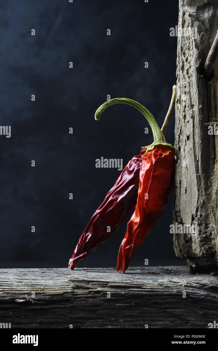Peperoncino essiccato peperoni in legno contro uno sfondo scuro Foto Stock