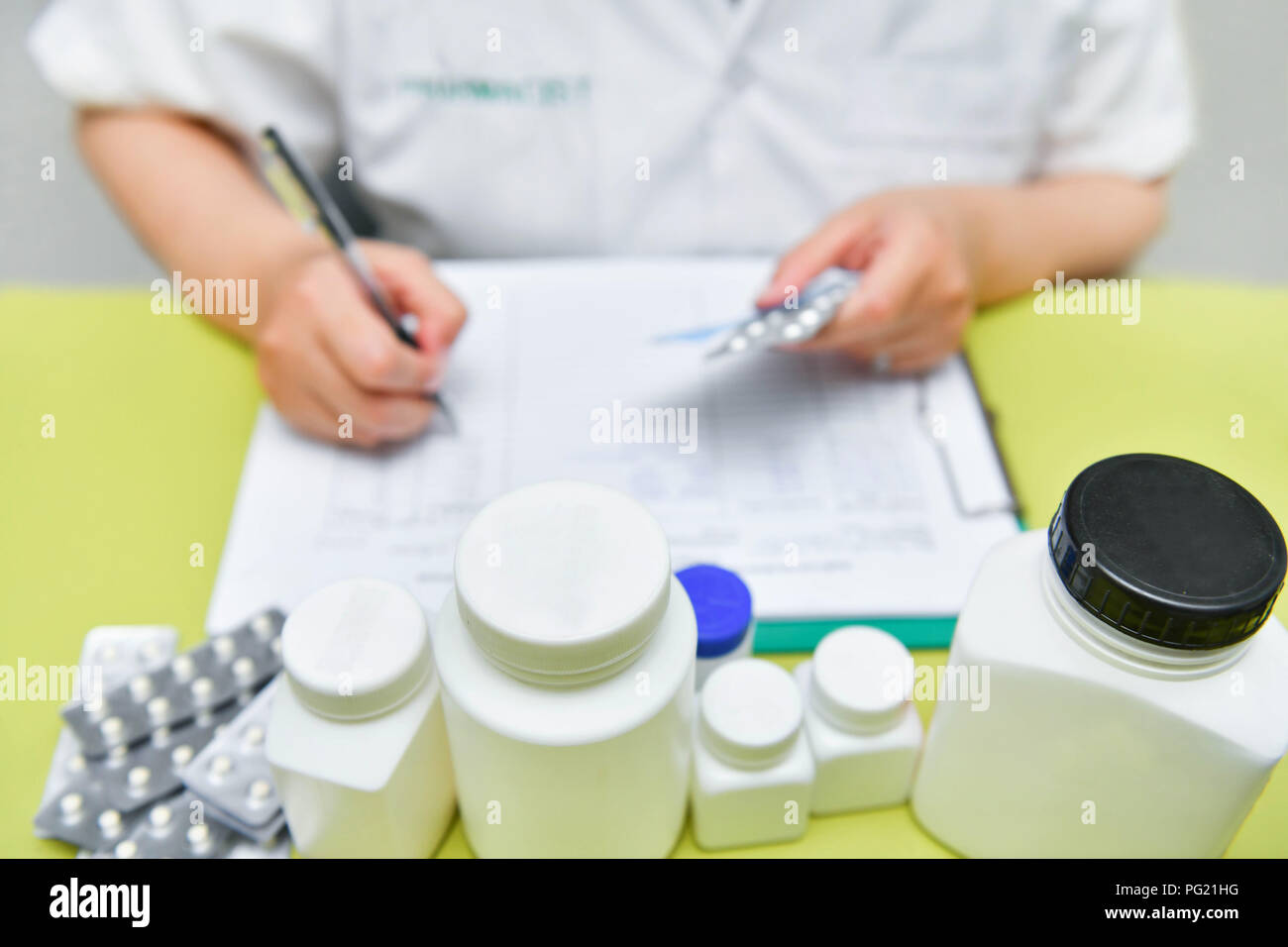 Vista ravvicinata di medico donna mano azienda pillole pack e la scrittura di prescrizione. Sanitario, medico e farmacia concetto. Foto Stock