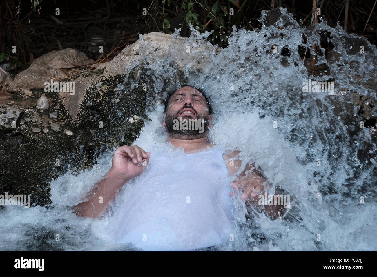 Un uomo palestinese godere di una sorgente di acqua di Ein Feshkha o Einot Tzukim riserva naturale chiamato per una molla di acqua salmastra in zona sulla costa nord-occidentale del Mar Morto Israele Foto Stock