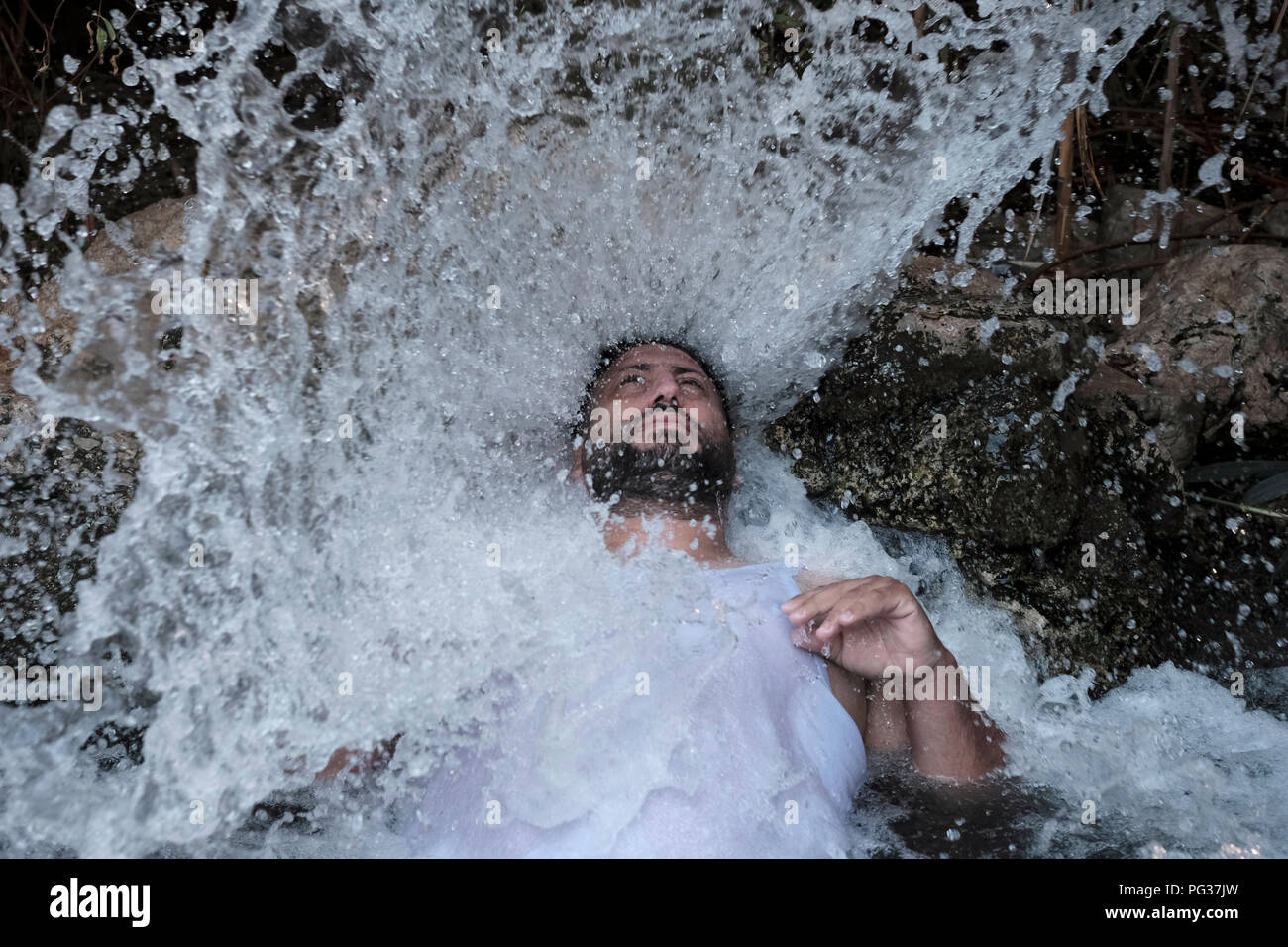 Un uomo palestinese godere di una sorgente di acqua di Ein Feshkha o Einot Tzukim riserva naturale chiamato per una molla di acqua salmastra in zona sulla costa nord-occidentale del Mar Morto Israele Foto Stock